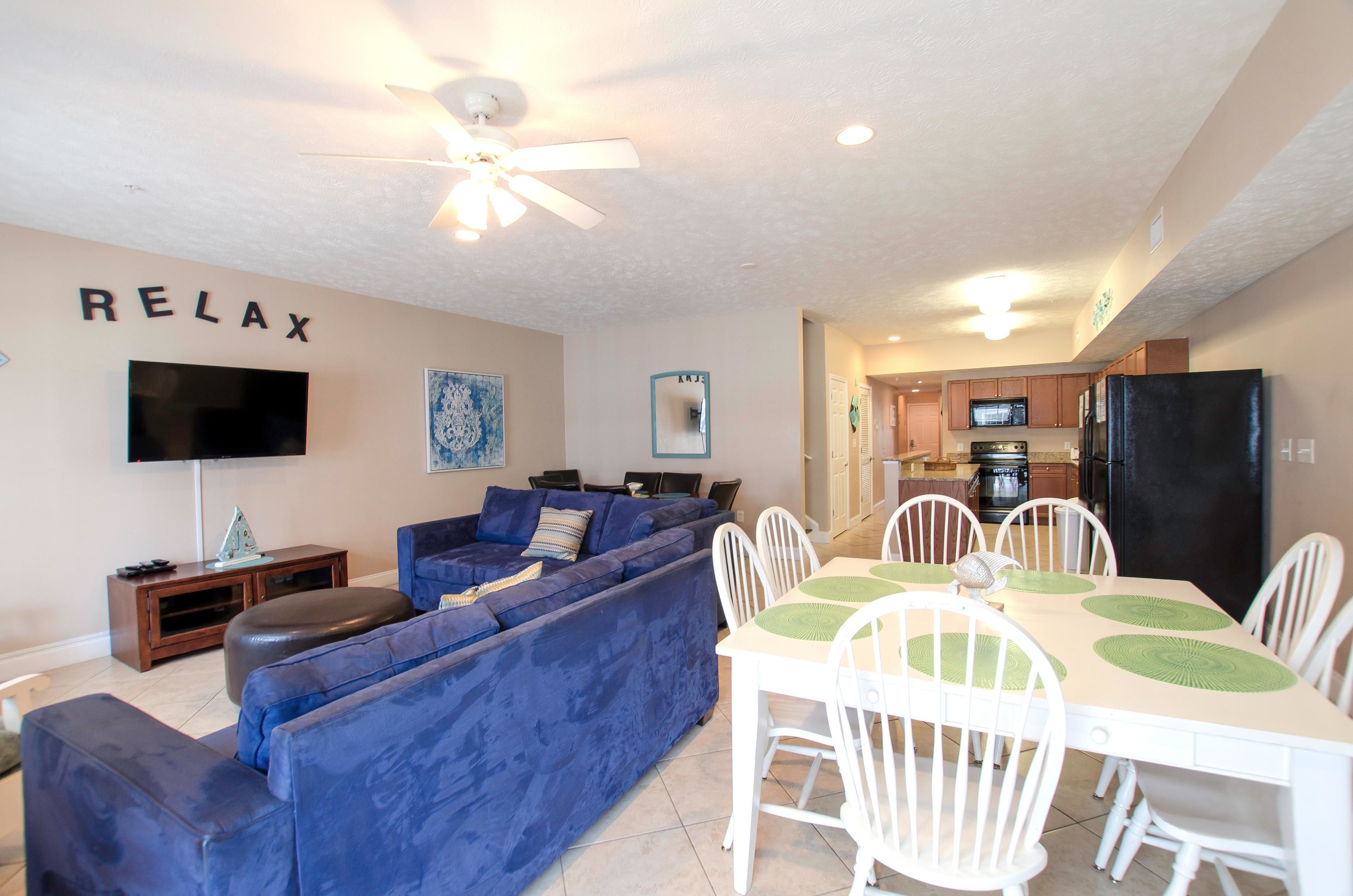 A living room with a blue sofa, a TV, and a 'RELAX' sign on the wall.