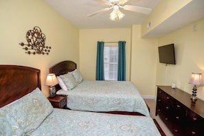 A bedroom with two beds, a ceiling fan, a TV, and a dresser. - Myrtle Beach 303B Villa Villa 6 (Myrtle Beach)