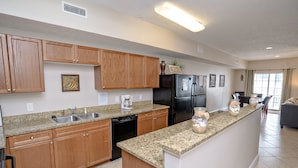 A modern kitchen with wooden cabinets, granite countertops, a black refrigerator, and a coffee maker. - Myrtle Beach 303B Villa Villa 6 (Myrtle Beach)