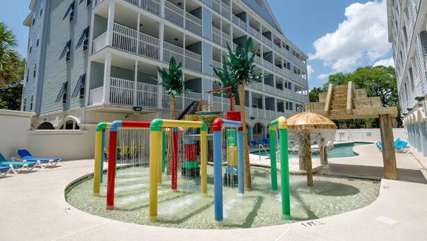 A hotel with a pool area featuring a water play structure and lounge chairs. - Myrtle Beach 303B Villa Villa 6 (Myrtle Beach)