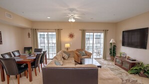 A living room with a sofa, dining table, chairs, a TV, and a ceiling fan. - Myrtle Beach 303B Villa Villa 6 (Myrtle Beach)