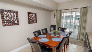 A dining area with a wooden table, black chairs, and decorative wall art. - Myrtle Beach 303B Villa Villa 6 (Myrtle Beach)