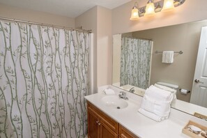A bathroom with a bamboo-patterned shower curtain, a sink with a mirror above it, and a towel rack with towels. - Myrtle Beach 303B Villa Villa 6 (Myrtle Beach)
