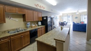 Una cocina con encimeras de granito, armarios de madera, lavavajillas y refrigerador.