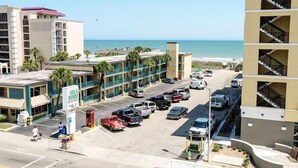 Un hôtel doté d’un parking, offrant une vue sur la plage et dont le bâtiment est surmonté d’un toit rouge.
