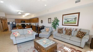 A spacious living room with two light blue sofas, a coffee table, and a dining area with a kitchen in the background. - Myrtle Beach 401A Villa Villa 4 (Myrtle Beach)