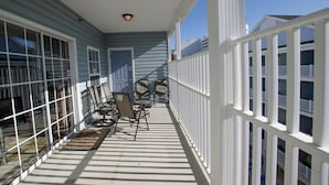 A covered porch with a railing, a door, and a seating area with chairs and a table. - Myrtle Beach 401A Villa Villa 4 (Myrtle Beach)