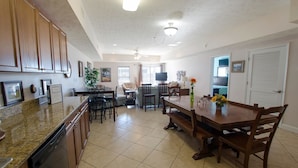 A spacious kitchen with granite countertops, wooden cabinets, and a dining area with a wooden table and chairs. - Myrtle Beach 401A Villa Villa 4 (Myrtle Beach)