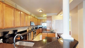 A modern kitchen with wooden cabinets, stainless steel appliances, and a granite countertop.