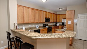 A kitchen with wooden cabinets, granite countertops, a microwave, a refrigerator, and a coffee maker. - Tuscan Ocean Vista B Holiday Home Holiday home 8 (Myrtle Beach)