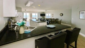 A modern kitchen with a large island, bar stools, and a view to the outside.