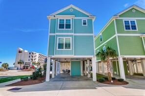 A two-story building with a green and blue facade, numbered 2701 and 2709, featuring a covered entrance with a palm tree and small shrubs.