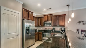 A modern kitchen with wooden cabinets, stainless steel appliances, and a granite countertop. - South Beach Cottages - 2701 Apartment 4 (Myrtle Beach)