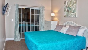A bedroom with a bed, a dresser, a lamp, and a painting on the wall. - Cherry Grove Villas - 204 Villa 6 (North Myrtle Beach)