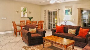 A living room with a dining area, a ceiling fan, and a large window with curtains. - Cherry Grove Villas - 204 Villa 6 (North Myrtle Beach)