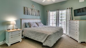 Ein Schlafzimmer mit Bett, Nachttisch, Kommode und Deckenventilator.