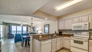 A modern kitchen with white cabinets, a granite countertop, a built-in oven, and a dishwasher.
