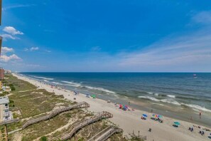 A beach with a wooden boardwalk, sandy beach, and ocean waves.