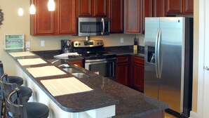 Una cocina con armarios de madera, un refrigerador de acero inoxidable, un microondas y una estufa.
