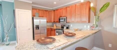 A modern kitchen with granite countertops, stainless steel appliances, and wooden cabinets.