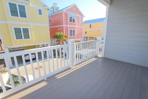 A balcony with a white railing, overlooking colorful buildings.