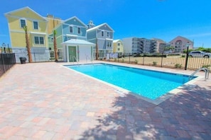 A swimming pool with a tiled deck, surrounded by colorful houses.