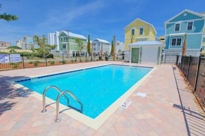 Une piscine avec un escalier en métal, entourée d’une terrasse en briques.