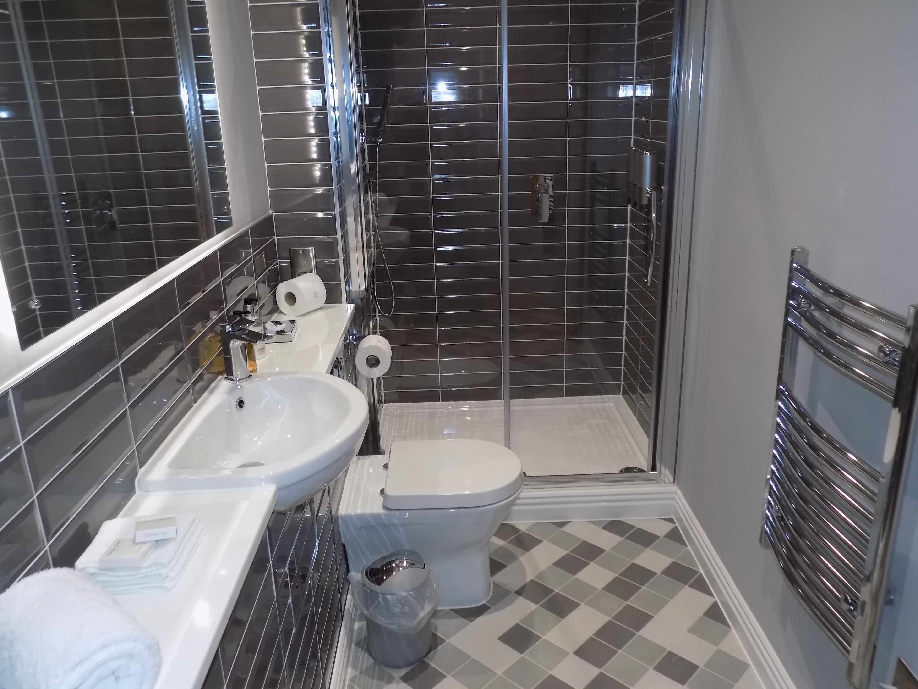 Une salle de bain moderne avec un lavabo, des toilettes et une douche, le tout de couleur blanche.