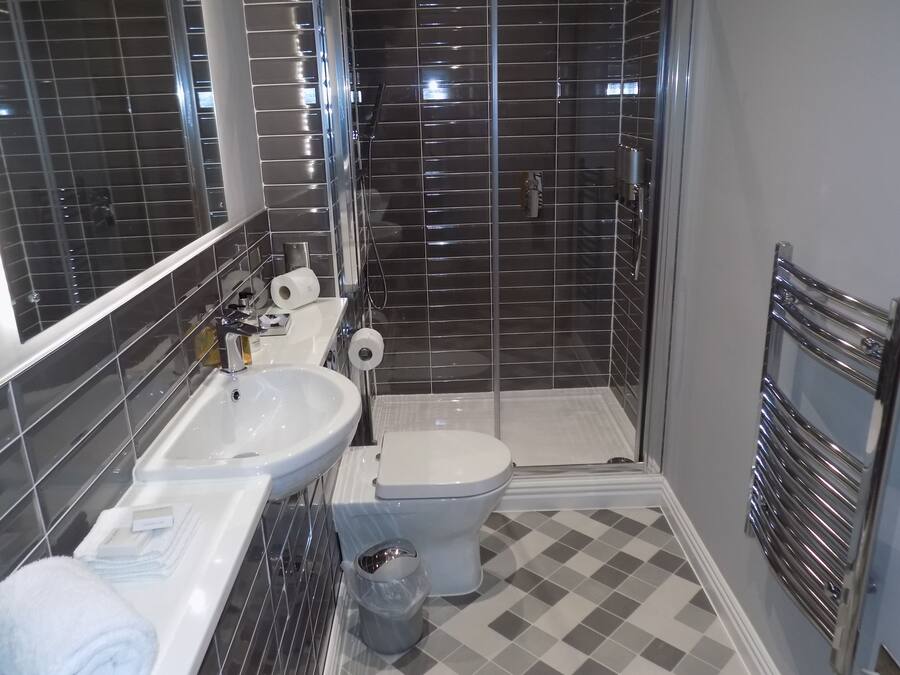 Un baño moderno con lavamanos, inodoro y ducha blancos.