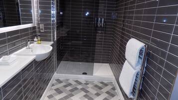 Un baño moderno con un lavamanos blanco, un espejo y una zona de ducha.