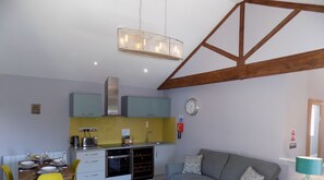 Una cocina compacta con zona de comedor, un sofá y un reloj en la pared.