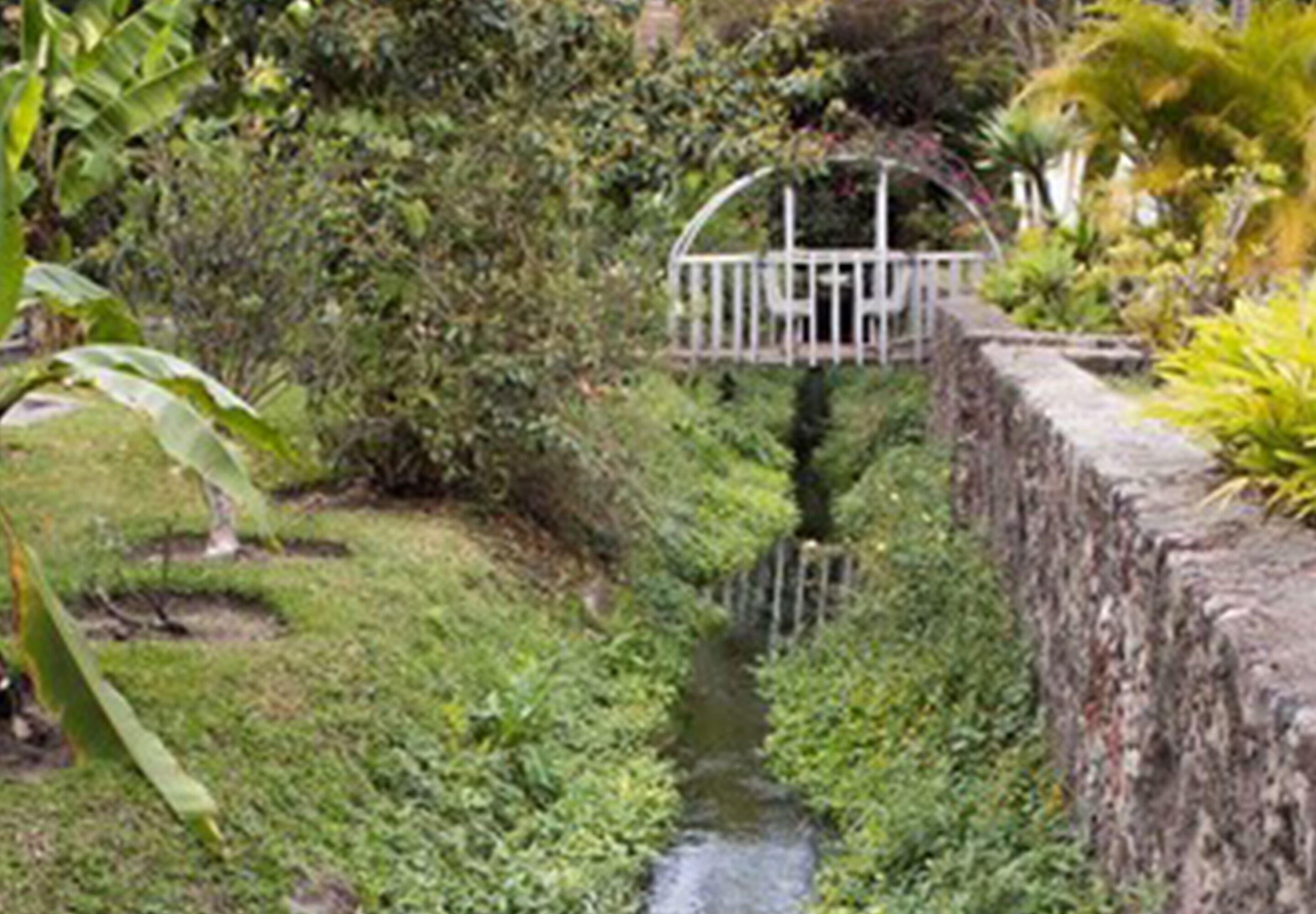 A narrow water channel with a bridge and stone wall.