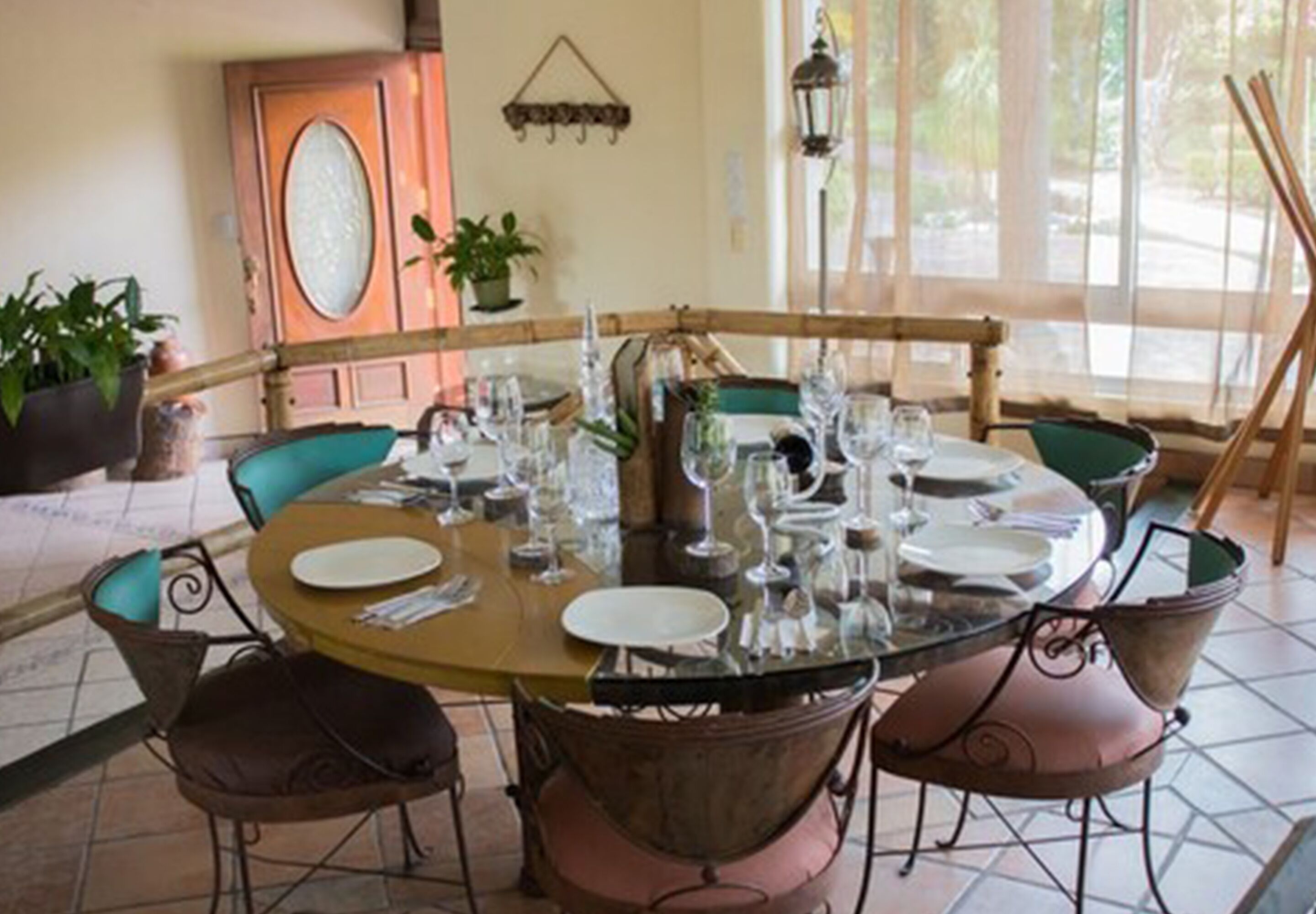 A round dining table set with plates, glasses, and cutlery, surrounded by chairs with cushioned seats.