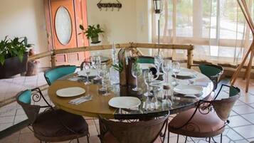 A round dining table set with plates, glasses, and cutlery, surrounded by chairs with cushioned seats.