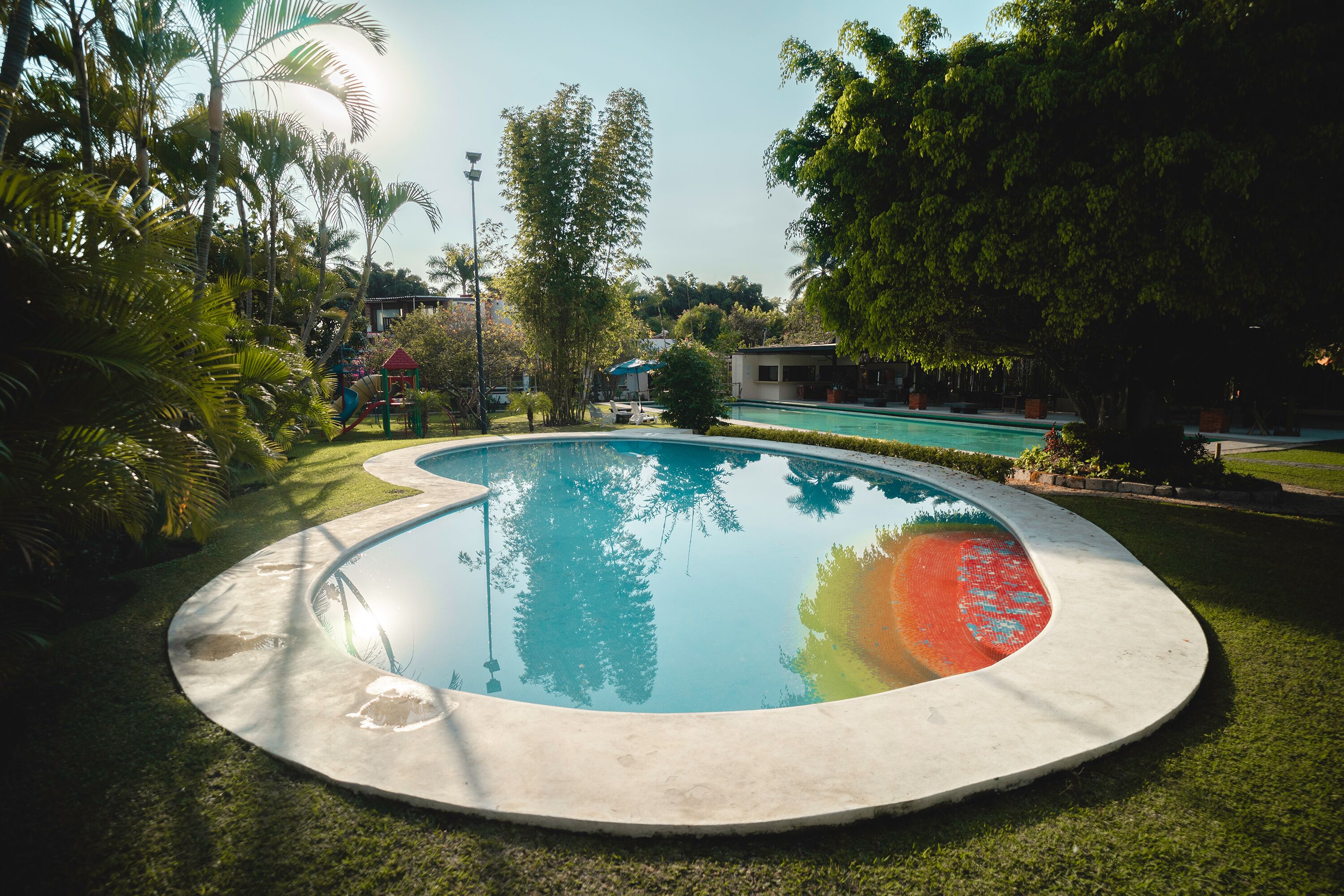 Una piscina circular rodeada de césped y árboles.