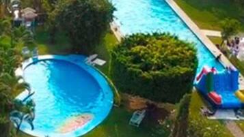 Una piscina rodeada de abundante vegetación y un tobogán.