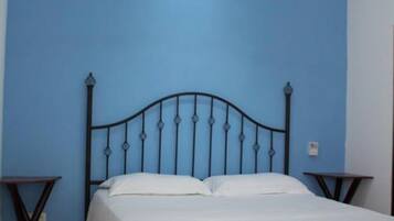 Un dormitorio con cama, ventilador de techo y dos mesitas de noche.
