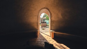 An arched doorway leading to an outdoor area with a brick floor and a small garden. - Hotel Quinta Moctezuma (Yautepec)