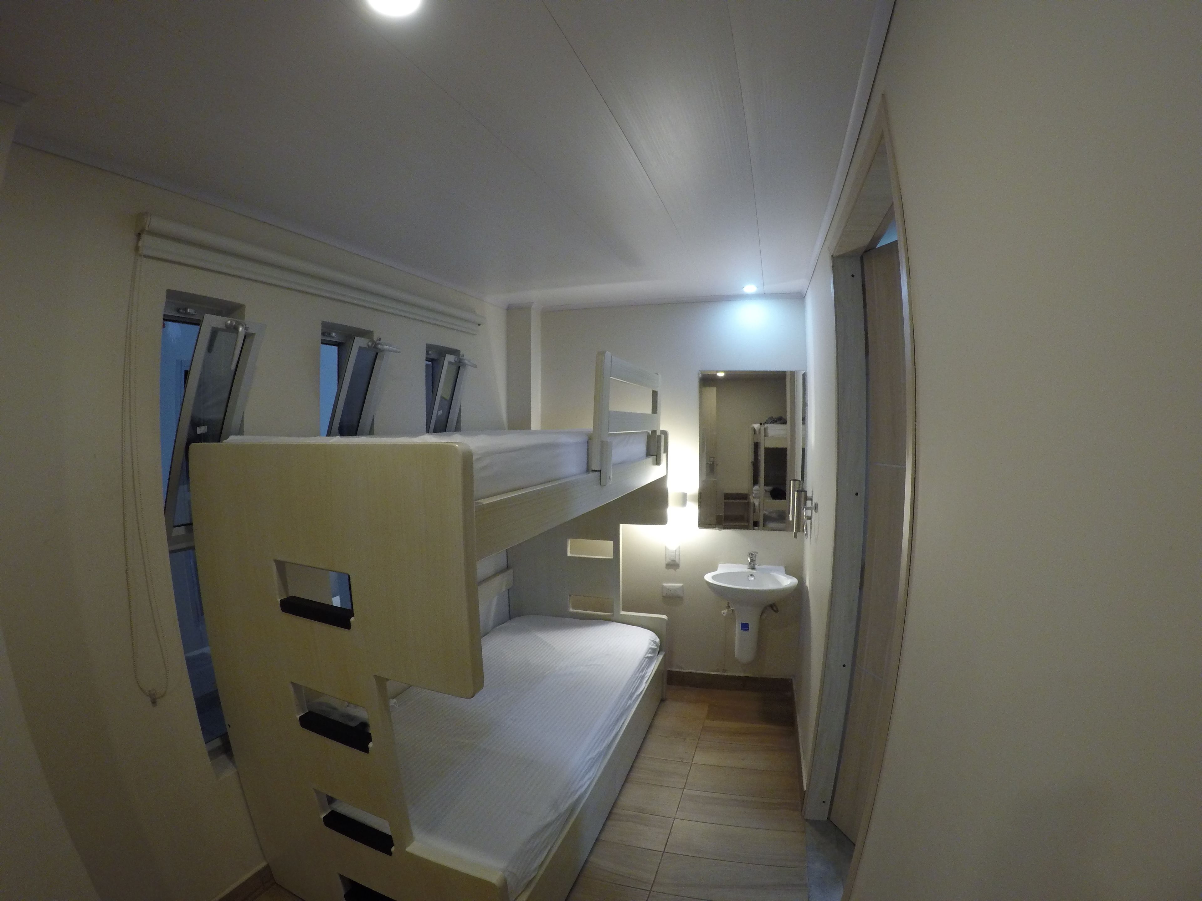 A small, compact room with bunk beds, a sink, and a mirror.