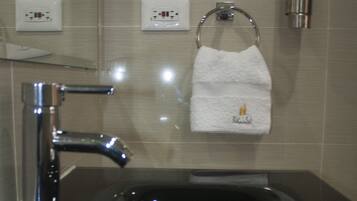 Un baño moderno con un lavabo negro, grifo cromado y un tocadereje con una toalla blanca.