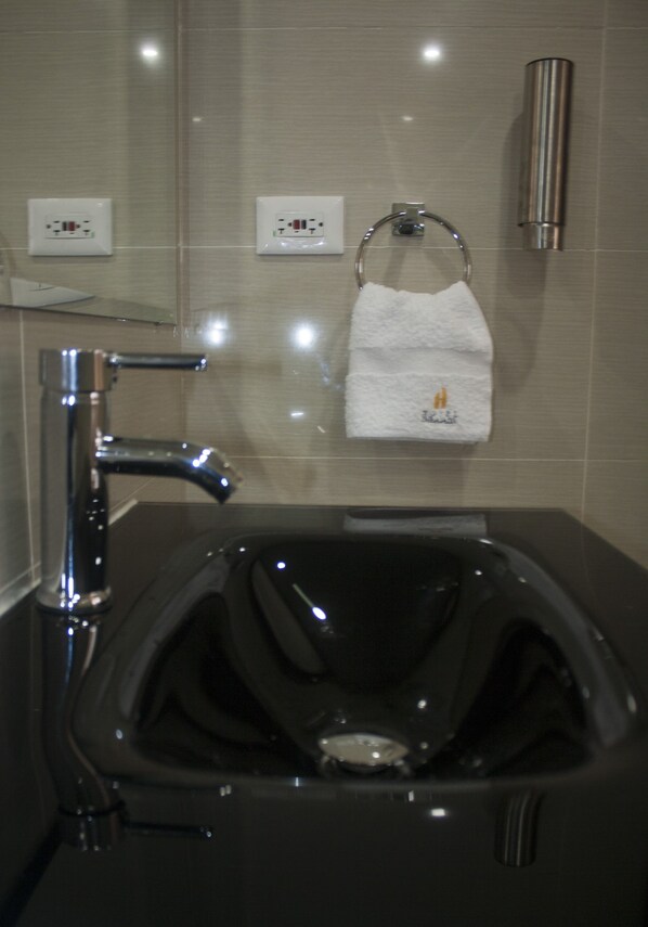 Un baño moderno con un lavabo negro, grifo cromado y un tocadereje con una toalla blanca.