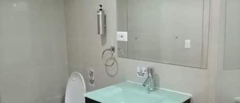 Un baño con inodoro, lavamanos y espejo.