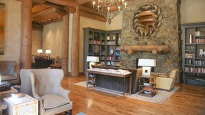 Un salon chaleureux avec une cheminée, des étagères à livres, un lustre et des fauteuils confortables.