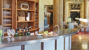 Un espace bar doté d’un comptoir incurvé, de bouteilles de vin, de verres, ainsi qu’un assortiment de fromages et de fruits.