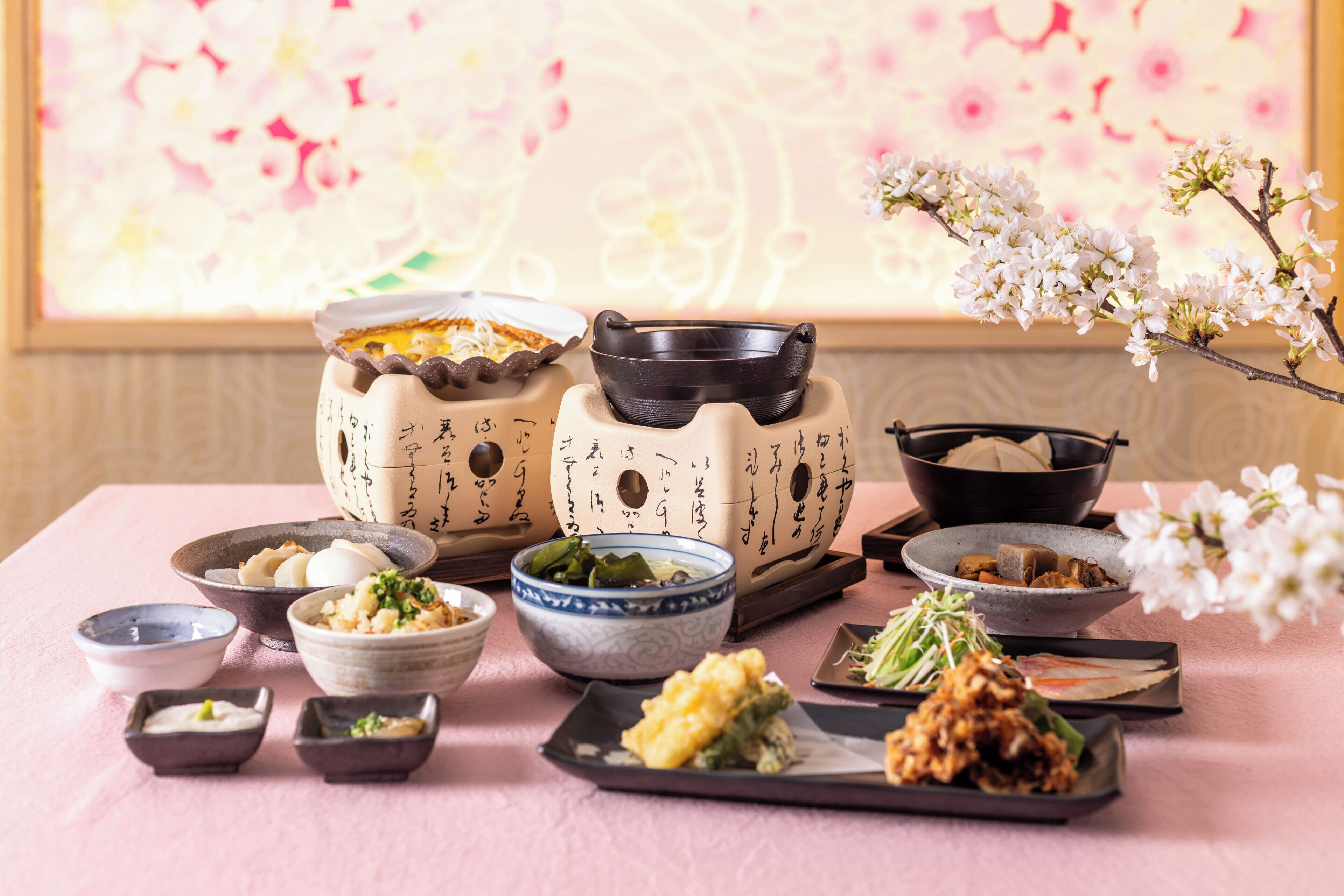 A table with various dishes and bowls, some with Japanese writing, and a vase with flowers.