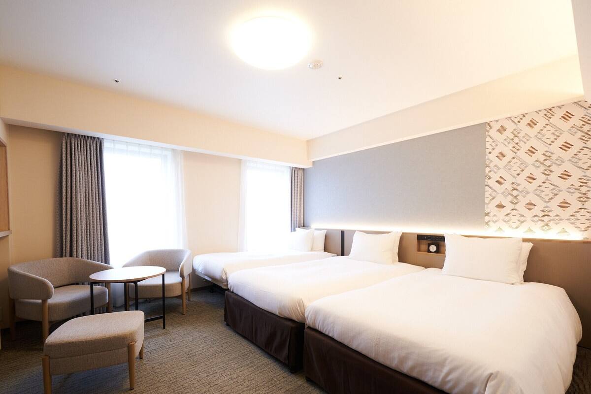 Een hotelkamer met twee bedden, een kleine tafel, een stoel en een bank.