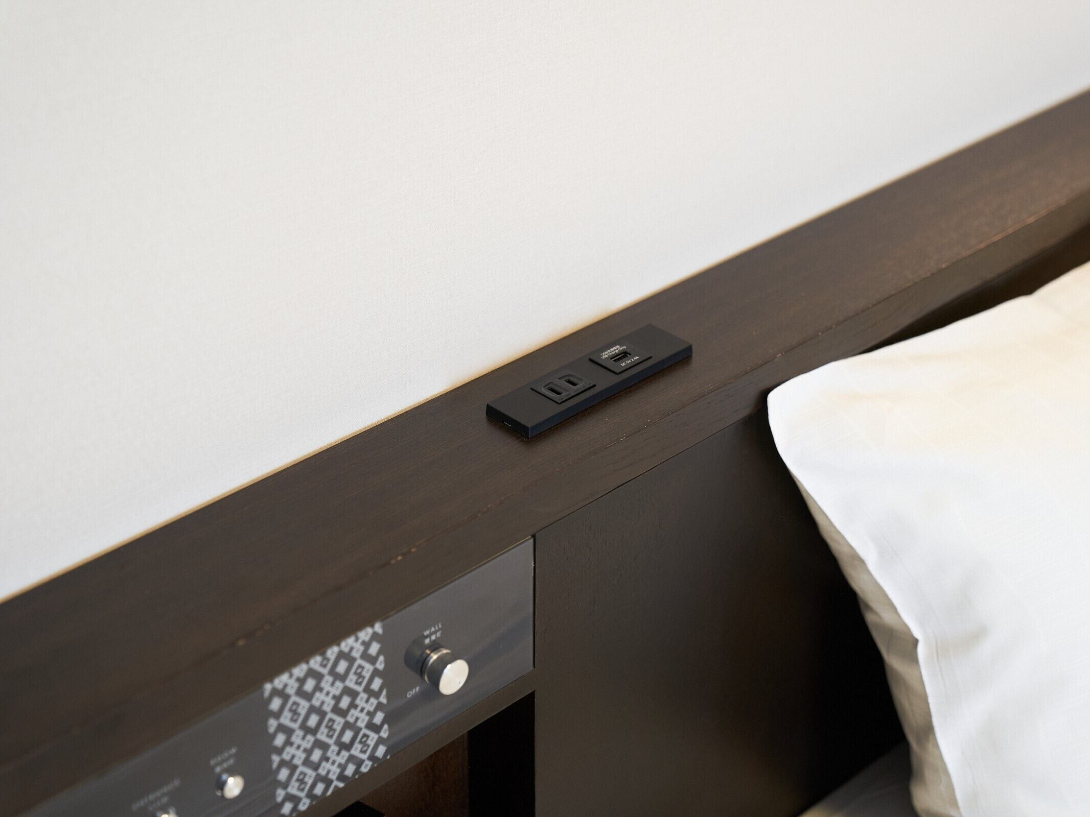 Una cama con un panel de control y un enchufe lateral.
