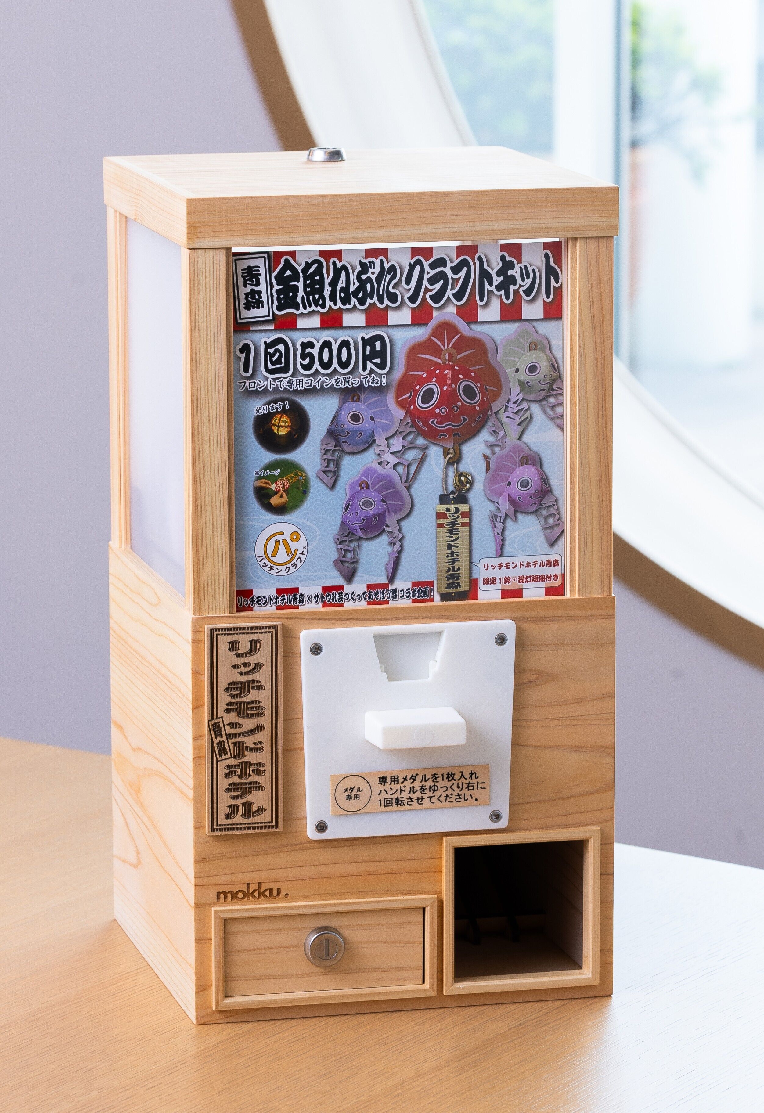 A wooden vending machine with Japanese text and a coin slot.