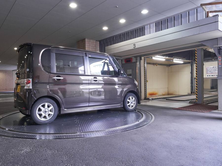 A compact car parked inside a building with a ramp leading to a garage.