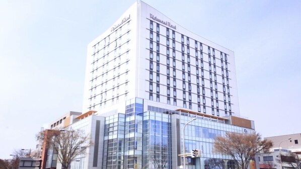 Un hôtel de grande hauteur, doté d’une façade moderne en verre, de nombreux étages et d’une enseigne bien visible au sommet.